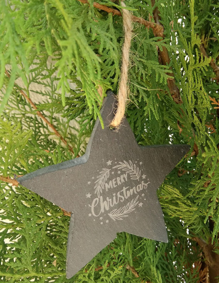 Adorno navideño con forma de estrella, de pizarra y con lazo para colgar. Ejemplo colgado en el árbol de Navidad.